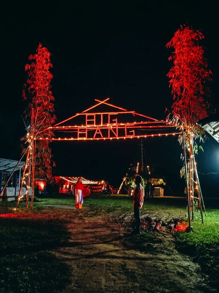 The bamboo festival gateway lit red at night, with dancers passing beneath it